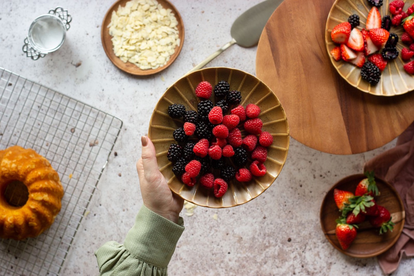 Plateau de fruits rouges, framboises et mûres présenté à la main, mise en scène éditoriale